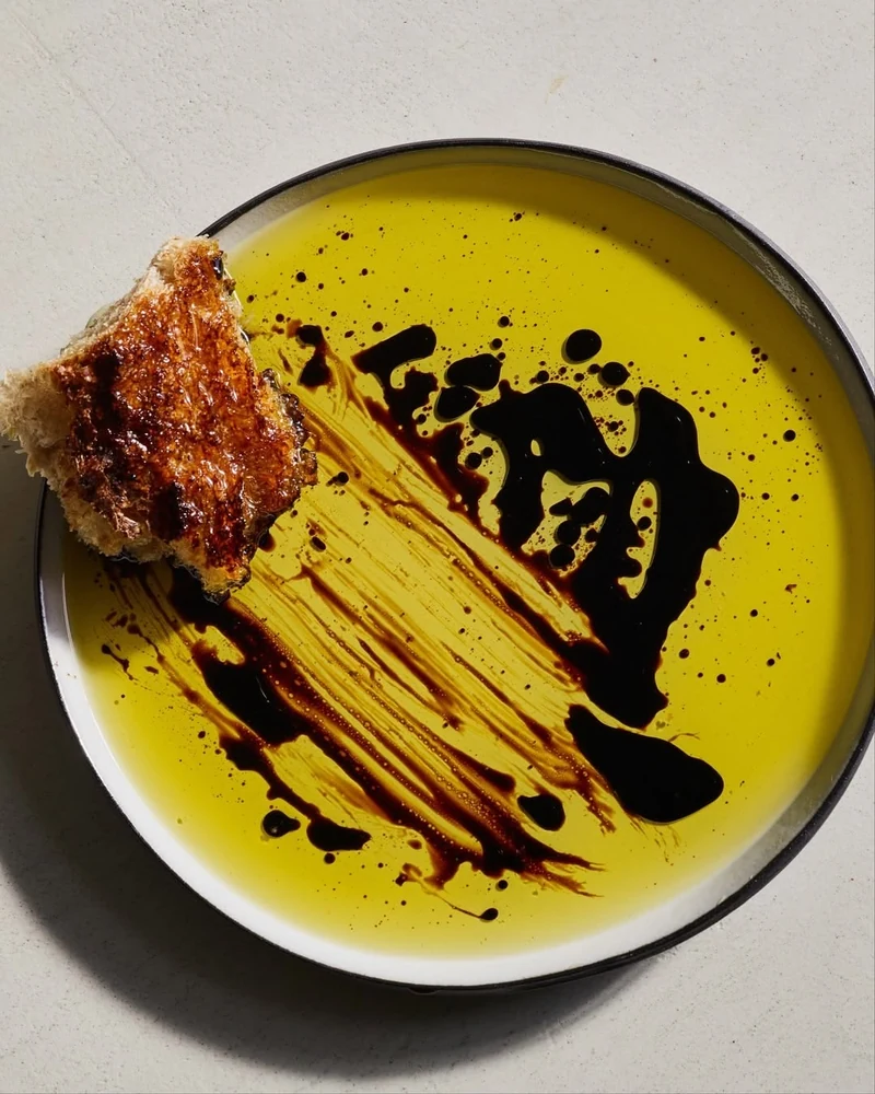 Morceau de pain trempé dans une assiette d’huile d’olive